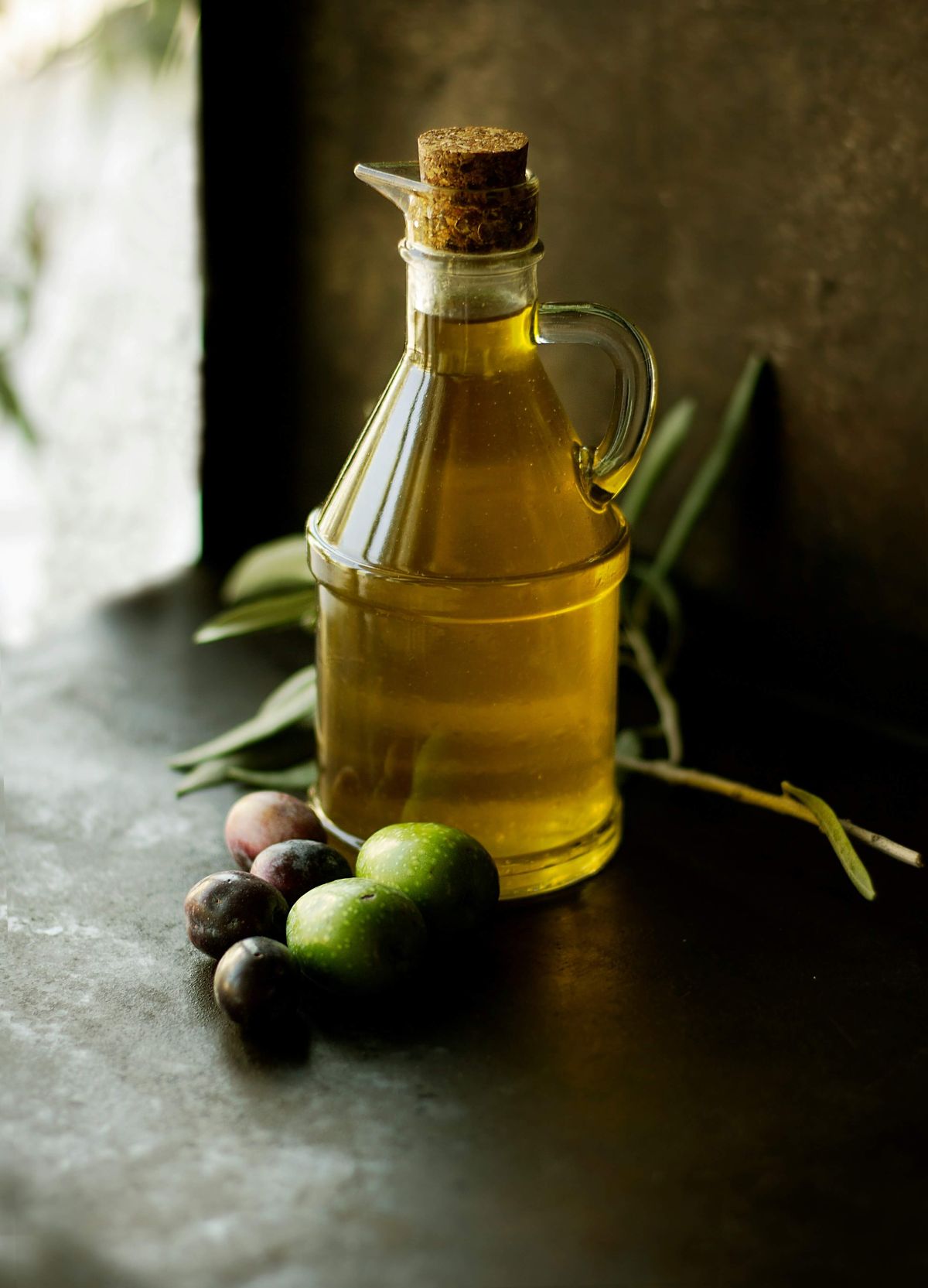 Extra vierge olijfolie in glazen fles met verse olijven